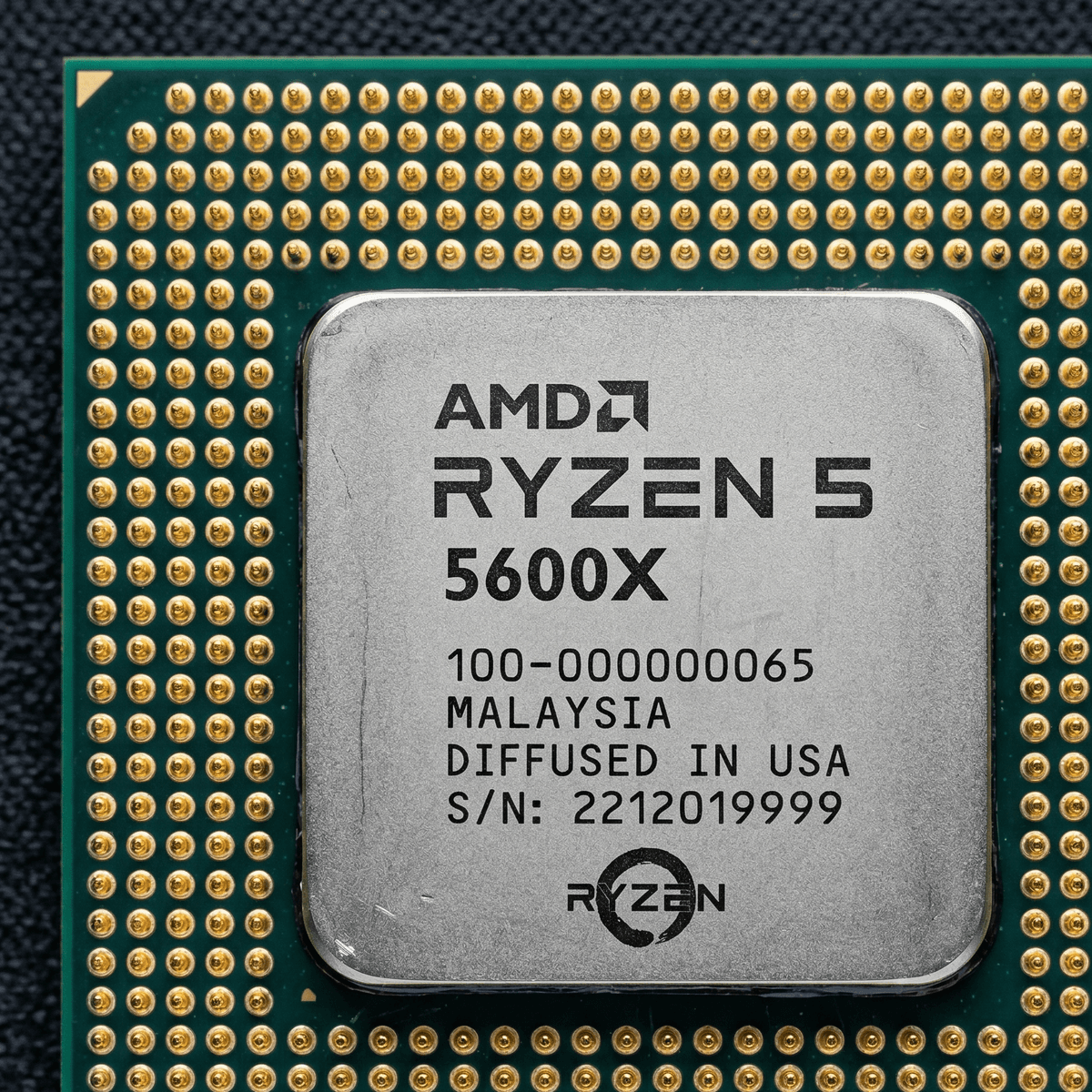 Close-up of a Ryzen 5 5600X IHS and contact pads under inspection lamp, clean condition